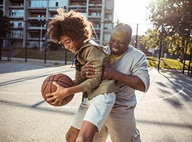 Padre e hijo divertidos jugando al baloncesto al aire libre