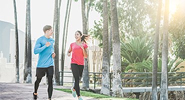 Couple running on path by palm trees