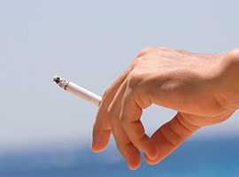 primer plano de una mano sosteniendo un cigarrillo encendido