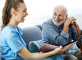 Enfermera sentada con un hombre mayor sonriente