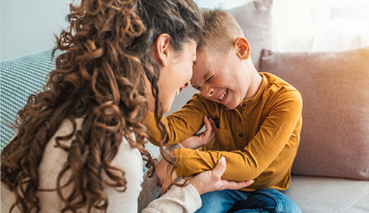 Mother and son on couch, heads together, laughing