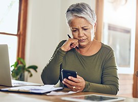 Mujer mayor concentrada en un smartphone y documentos