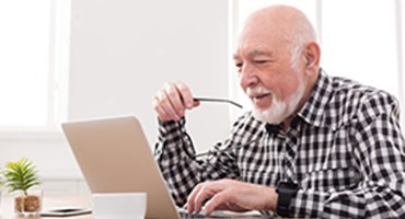 Member Portal Man sitting at kitchen table viewing laptop computer
