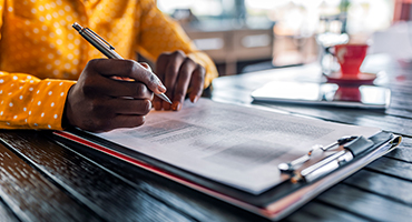 close up of hands filling out a form on clipboard