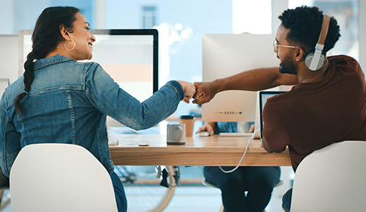 Trabajadores sentados en el escritorio chocando los puños