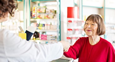 mujer con camisa roja en el mostrador de la farmacia