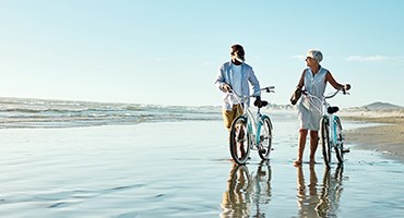 Couple walking their bikes on a beach