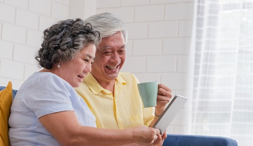 senior couple drinking coffee and reading tablet