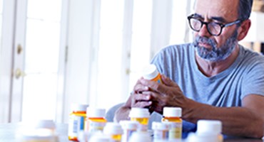 Man looking at a pile of Rx bottles