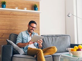 Man sitting on couch in den, looking at tablet computer